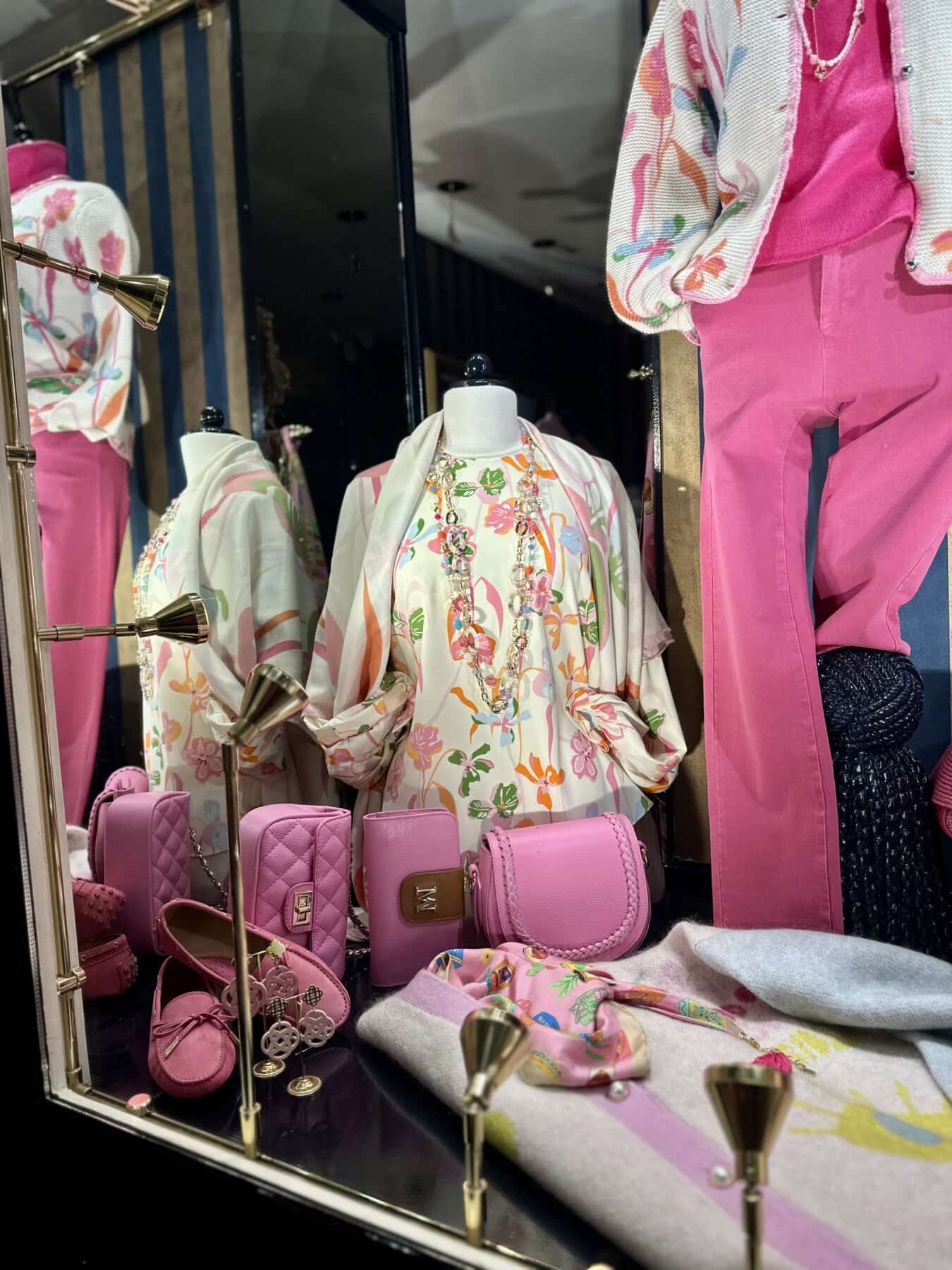 Modici etalage met kleurrijke dameskleding en accessoires in een winkel.