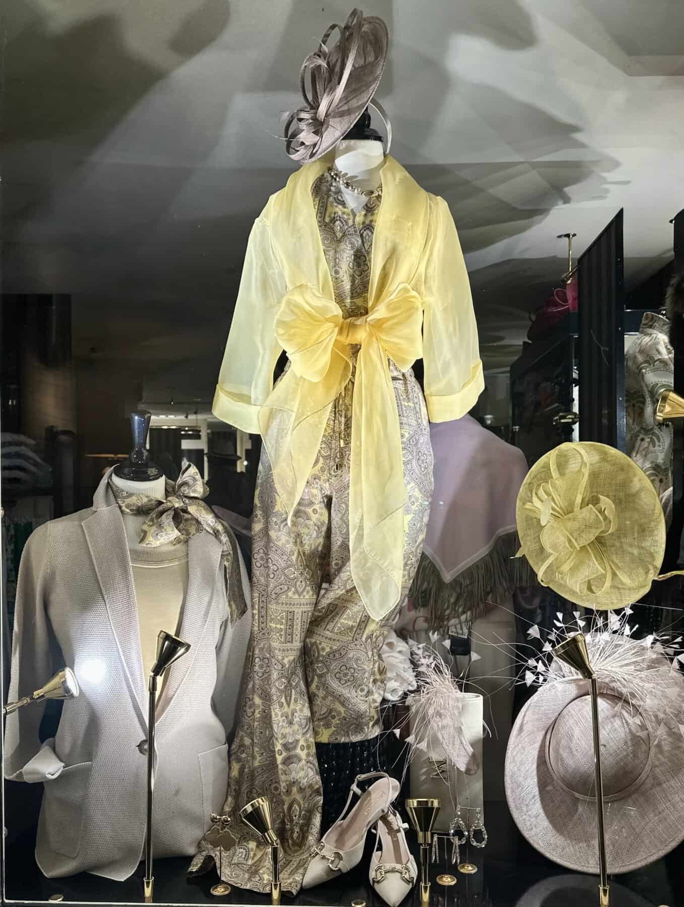 Modici, stijlvolle damesmode met elegante hoeden en accessoires in een winkelshowcase.